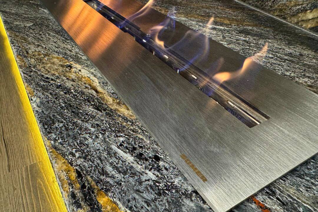 Sala de estar com lareira ecológica Somer instalada em nicho de pedra.